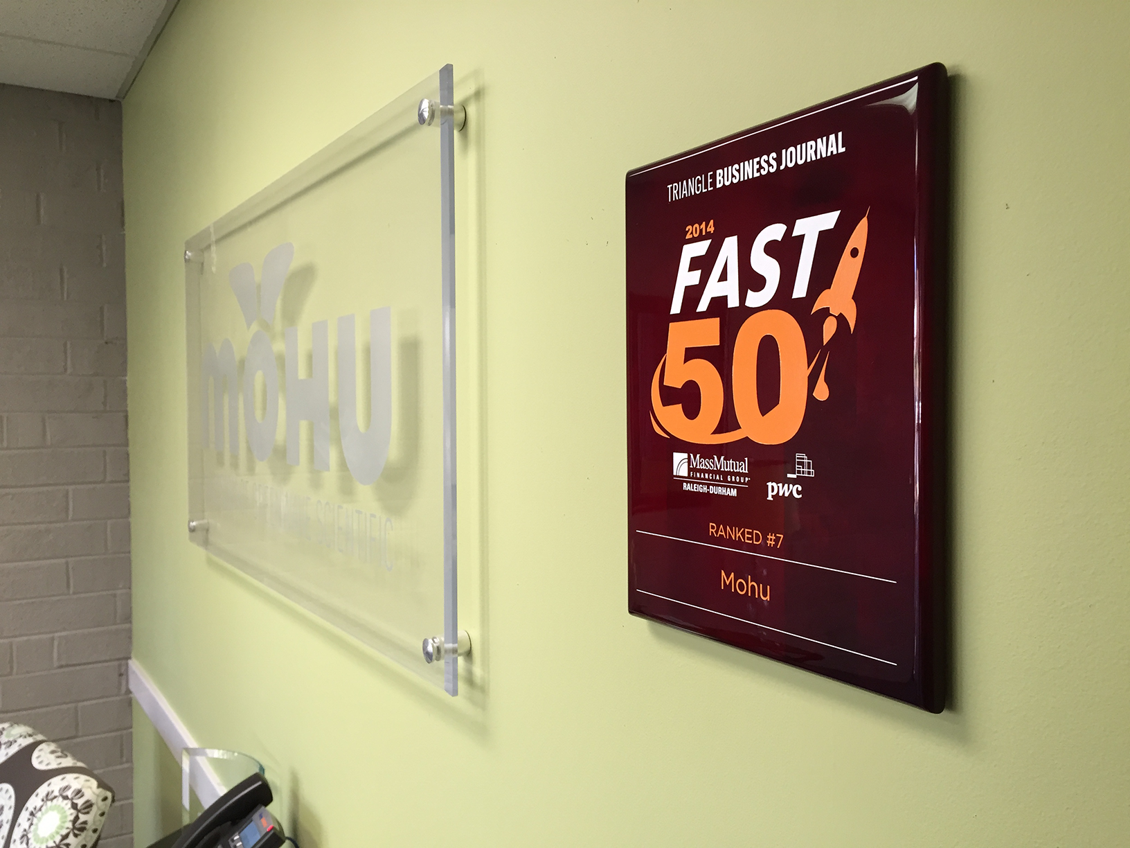 Mohu office- 2014 Triangle Business Journal Fast 50 Award hanging on a light green wall next to a Mohu sign